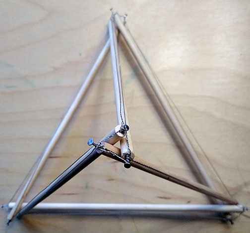 Photograph of a tensegrity tetrahedron made with 9" struts of 1/4" dowel and 28 gauge stainless steel wire.